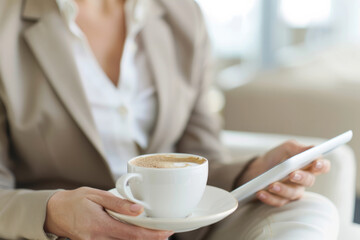 Wall Mural - a businesswoman planning her schedule with a digital tablet and a cup of coffee