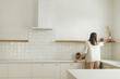 © sonyachny - Stylish woman with her cat unpacking and decorating shelves with utensils in new minimal white kitchen. Housewife cleaning up kitchen after moving in with cute pet in new modern home