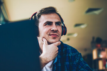 young good looking positive male person enjoying recreation with big modern headphones and modern de