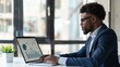 © Plaifah - A businessman reviewing stock market data on a laptop screen while working in a modern office environment