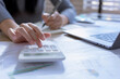 © kanpisut - Business woman or accountant working on calculator to calculate business data in modern office. Accounting business woman are calculating analyzing investment data, Financial and tax systems concept