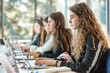 © Ilia Nesolenyi - Multiple female students sitting at a table, working on laptops with focused expressions