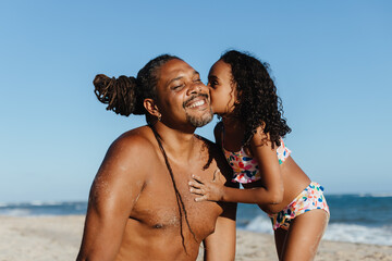 Wall Mural - Loving moment between dad and daughter on the beach with a kiss