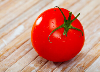 Wall Mural - One fresh juicy red tomato placed on wooden table.