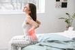© Pixel-Shot - Young woman suffering from back pain in bedroom