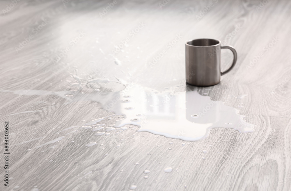 Wooden laminate floor with overturned cup of milk