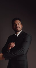 Wall Mural - Vertical clip. Portrait of handsome young Asian businessman in a black suit. Isolated on black background in studio.