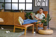 © Pixel-Shot - Male author with paper sheets lying in armchair at home