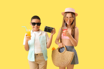 Poster - Cute little children in sunglasses with glasses of juice and camera on yellow background