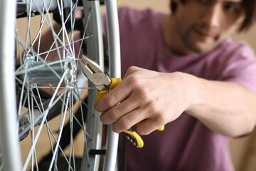 Wall Mural - Young man repairing his wheelchair with pliers at home, closeup