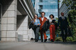 © qunica.com - A diverse group of business professionals walking confidently in an urban setting, laughing and enjoying their day.