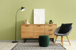 © Pixel-Shot - Chair, pouf, floor lamp and wooden chest of drawers near green wall in modern room