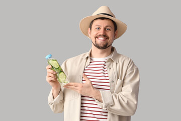 Canvas Print - Young man with bottle of cucumber water on light background