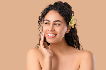 Poster - Beautiful young African-American woman with yellow orchid flower in her hair on brown background