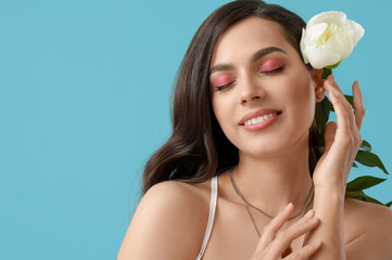 Poster - Beautiful young woman with white peony flower on blue background