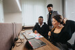 © qunica.com - Diverse team of young professionals collaboratively working on a project while using a laptop in a contemporary designed office space.