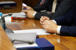 © slexp880 - Man in a business suit holds glasses in his hands next to a document while sitting at a table with his colleagues. Teamwork. Businessman, official or lawyer. Selective focus. No face