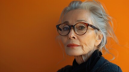 Wall Mural - Portrait of an older professional woman with a serious look, against a lively orange background