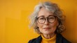 © WS Studio 1985 - Portrait of an older professional woman with glasses, against a bright, cheerful yellow background