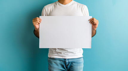 Person in a white tee presenting an empty sign with copy space against a blue background