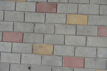 Poster - Dusty surface of gray, pink and yellow concrete pavement with stretcher bond pattern