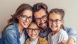 © Dina Photo Stories - Happy caucasian family of four wearing eyeglasses on light grey background. Smiling mother, father, son and daughter wearing glasses in various frames. Optics store, family clinic promotion