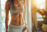 Close-up shot focusing on the belly of a beautiful woman, wearing workout clothes, pose and showcasing her flat and toned belly, with defined muscles, blurred background