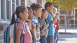 © Felippe Lopes - Diverse group of children with backpacks smiling and standing in a row outside a school building on a bright sunny day.
