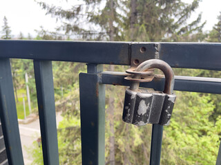 Old padlock on a metal fence in the background of the forest