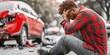 © Boomanoid - Man sitting next to wrecked car on roadside