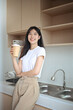 © Prathankarnpap - Charming young Asian woman enjoying fresh aromatic coffee standing in the kitchen