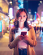 © homydesign - Happy lady observing phone city night