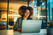 © VisualProduction - A confident young Afro-American woman typing on her laptop in a modern office flooded with natural light, her determined expression illuminated by the glow of her computer screen.