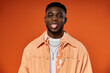 © LIGHTFIELD STUDIOS - A fashionable, young African American man sticks out his tongue while wearing a stylish orange jacket.