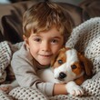 © authapol - A little boy cuddling with a puppy on a soft blanket, both looking content and happy, showcasing the bond between a child and a pet