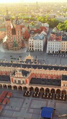 Wall Mural - Main Market square or Rynek Glowny with a Town Hall, Sukiennice and St. Mary's Basilica church at sunrise in Krakow, Poland. Aerial view of the Krakow central square in morning. 