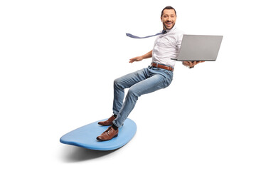 Man holding a laptop computer and riding a surfboard