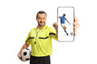 © Ljupco Smokovski - Football referee holding a ball and showing a smartphone with a football player on screen