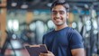 © LukaszDesign - In gym, personal trainer with clipboard advises sports customer. Muscular, athletic, and smiling fitness coach shares health, wellbeing, and exercise with flair.