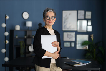 Sticker - Successful mature businesswoman standing confidently in office, professional smile, thriving in corporate environment.