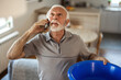 © Jelena Stanojkovic - Elderly man calling plumber for water leakage at home.