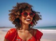 © Johnovich - Beautiful black woman in red dress on the beach. African woman in red sundress and sunglasses having fun on the beach