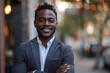 © SITI - Confident young African American executive corporate manager leader outdoors, smiling professional businessman with short hair in grey suit standing with arms crossed