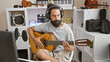 © Krakenimages.com - Hispanic man playing guitar in a home music studio with microphone and headphones