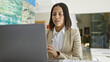 © Krakenimages.com - Focused hispanic businesswoman working on laptop in modern office with art on the wall.