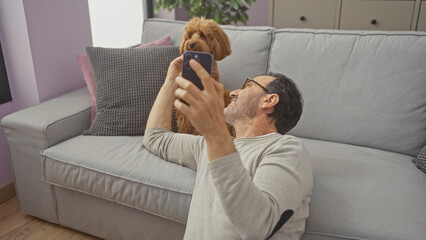 Poster - A middle-aged hispanic man and his poodle are taking a selfie in the living room of a modern apartment.