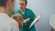 © Krakenimages.com - Hispanic veterinarian consults with a woman holding a poodle inside a clinic room.