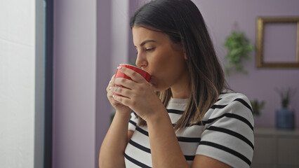 Canvas Print - A pensive hispanic woman sips coffee indoors, surrounded by home decor in a cozy apartment.