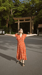 Poster - Joyful hispanic woman smiling with open arms, looking around at meiji temple, showcasing confidence and happiness