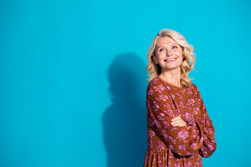 Wall Mural - Photo of charming positive woman wear brown dress arms crossed looking back empty space isolated blue color background